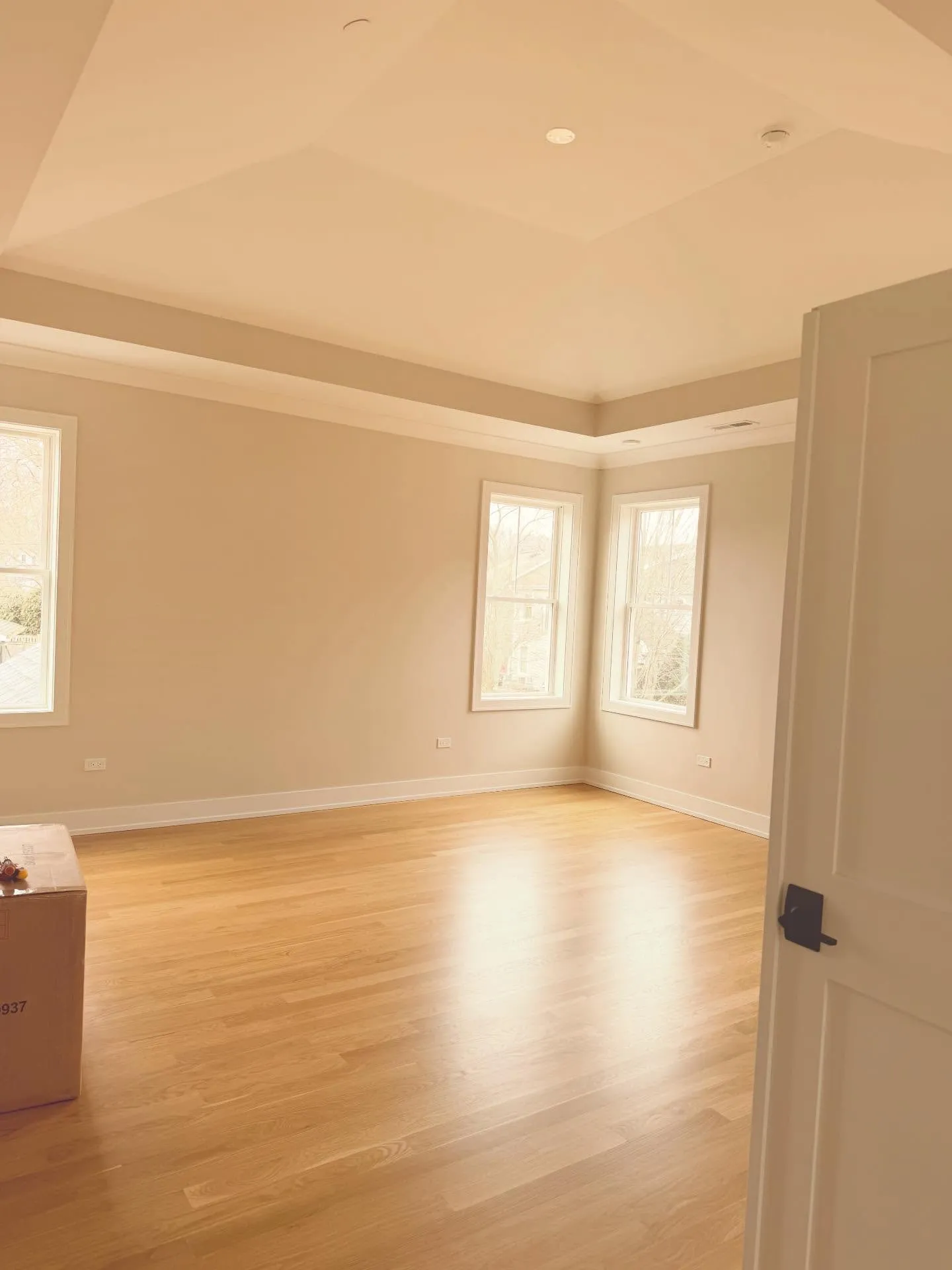 Primary bedroom — tray ceiling, crown molding, refinished white-oak floors