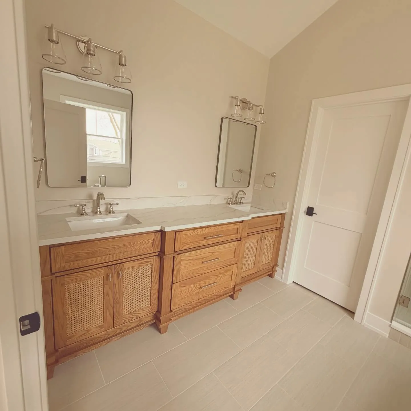 Primary bath — oak double vanity with cane doors, quartz top, polished-nickel fixtures