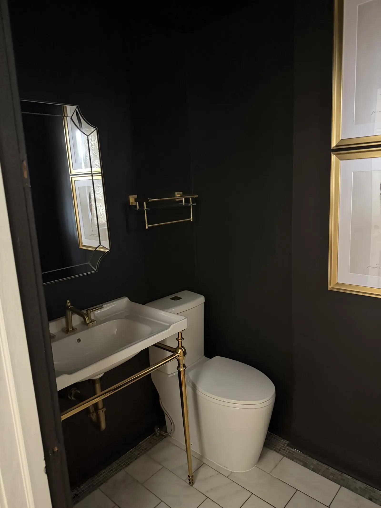 Powder room detail — dramatic dark walls, brass mirror and hardware